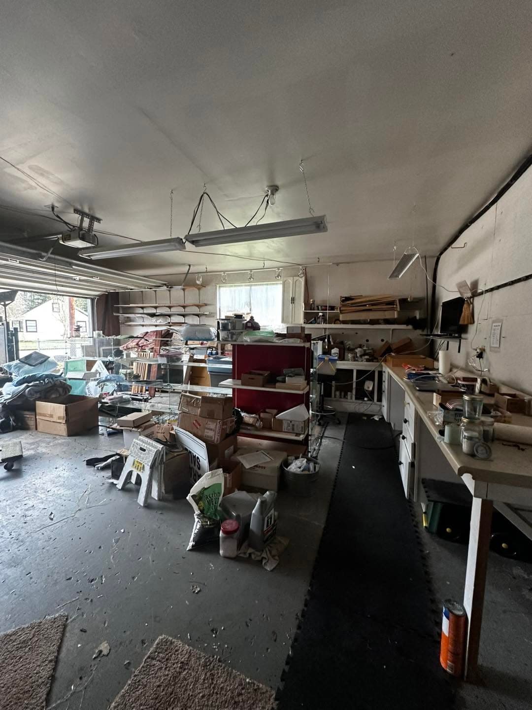 Cluttered garage filled with boxes, tools, and various items, showcasing a disorganized workspace.