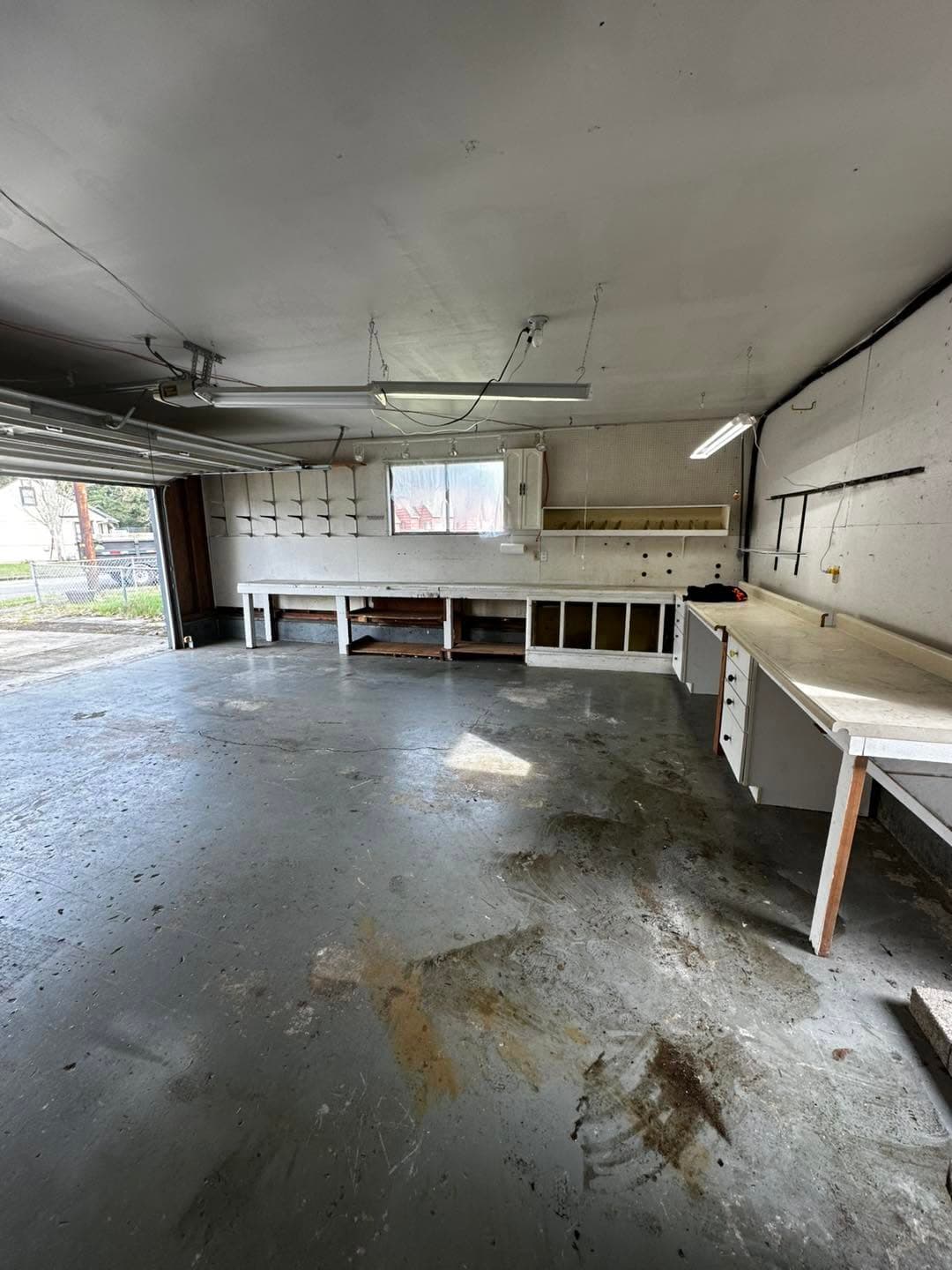Spacious garage interior with workbenches and natural light from a window.